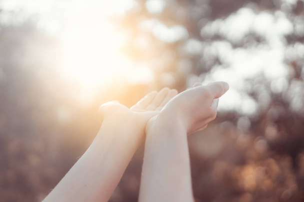 Frau offene Hand bis zum Sonnenuntergang Himmel und grüne Unschärfe Blatt Bokeh Sonnenlicht abstrakten Hintergrund. - Foto, Bild