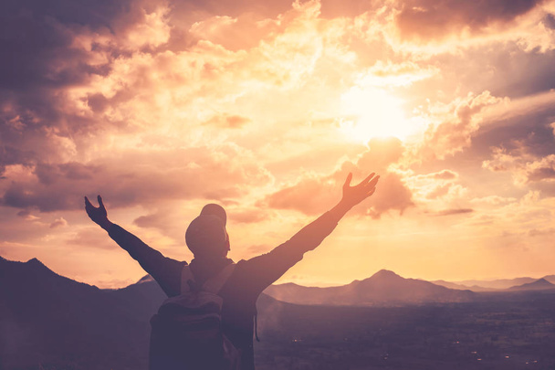 Backpacker человек поднять руку на вершине горы с неба заката и облака абстрактный фон
. - Фото, изображение