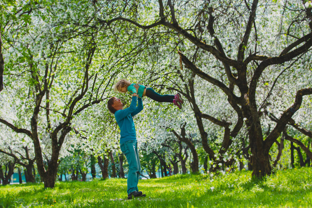 feliz padre e hija juegan en la naturaleza de primavera, la familia disfruta de la flor de manzana
 - Foto, imagen