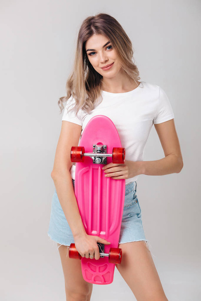 beautiful woman in white t-shirt with pink skateboard - Foto, afbeelding