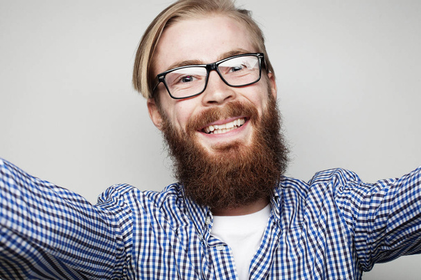 Portrait of  young bearded  man taking selfie and holding camera  - Fotoğraf, Görsel