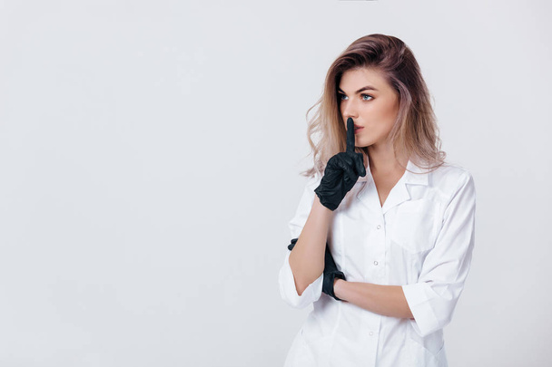 cosmetologist in black gloves shows sign silence. Woman beautician doctor - Foto, Imagem