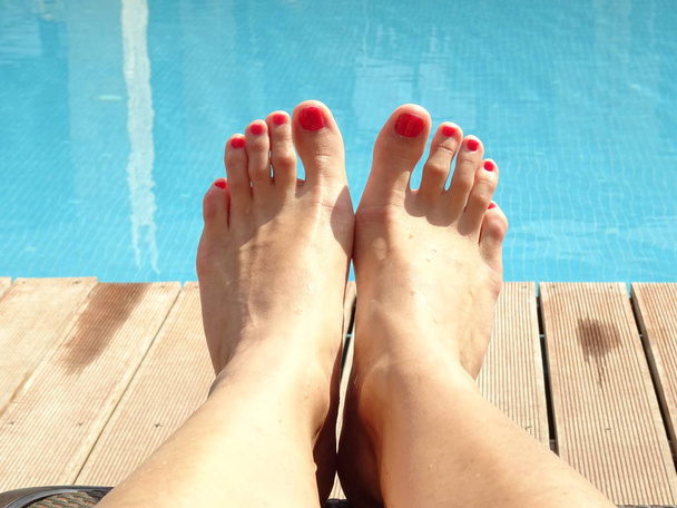Female Feets with Red Nailpolish in front of a Swimming Pool - Фото, изображение