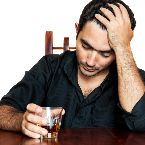 Hispanic man holding an alcoholic drink and suffering a headache - Foto, afbeelding