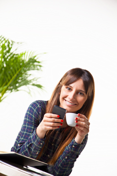 Mujer joven sonriente con un café y sujeto a un teléfono
 - Foto, Imagen