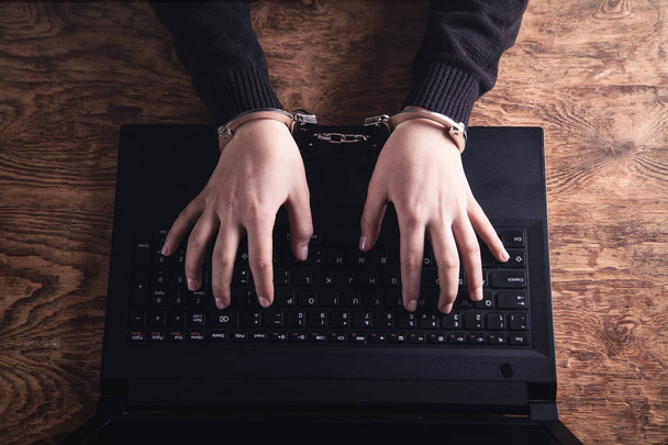 Руки в наручниках, печатающие на клавиатуре. Концепция киберпреступности
 - Фото, изображение