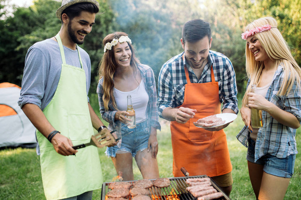 Cheerful friends spending time in nature and having barbecue - Foto, imagen