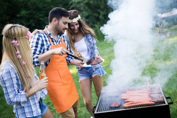 Friends making a barbecue together outdoors in the nature - 写真・画像