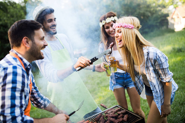 Cheerful friends spending time in nature and having barbecue - Foto, Bild