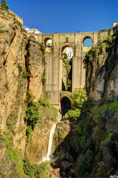 Blick auf die tiefe Grube von Ronda, Malaga (Spanien). Dieser vom Fluss Guadalevn ausgegrabene Schnitt teilt die Stadt in zwei Teile. Hier sehen Sie die Brücke, die gebaut wurde, um die beiden Teile zu vereinen. - Foto, Bild
