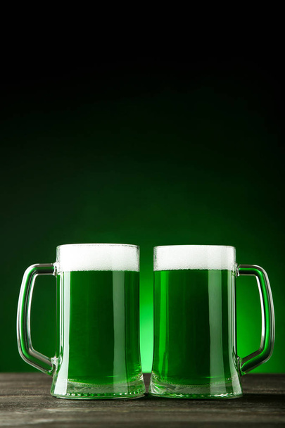 Dia de São Patrício. Canecas de vidro com cerveja verde no fundo escuro
 - Foto, Imagem