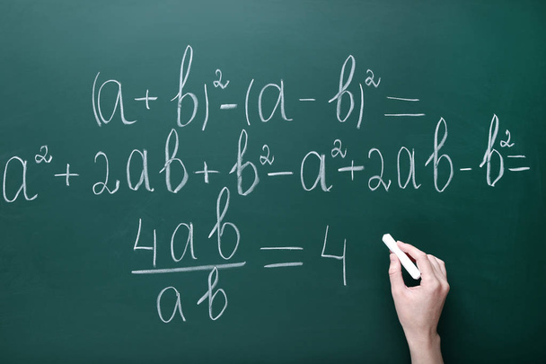 Female hand writing maths formulas on chalkboard - Photo, image