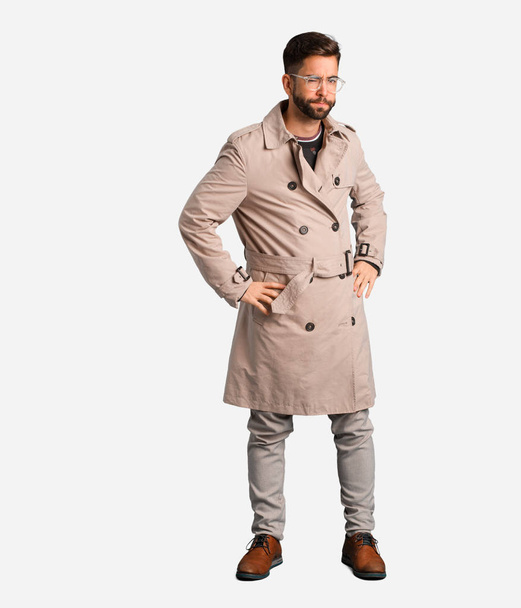 Young man wearing trench coat scolding someone very angry - Zdjęcie, obraz