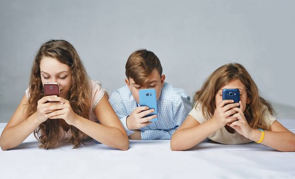 a children are focused on playing smartphones. - Valokuva, kuva
