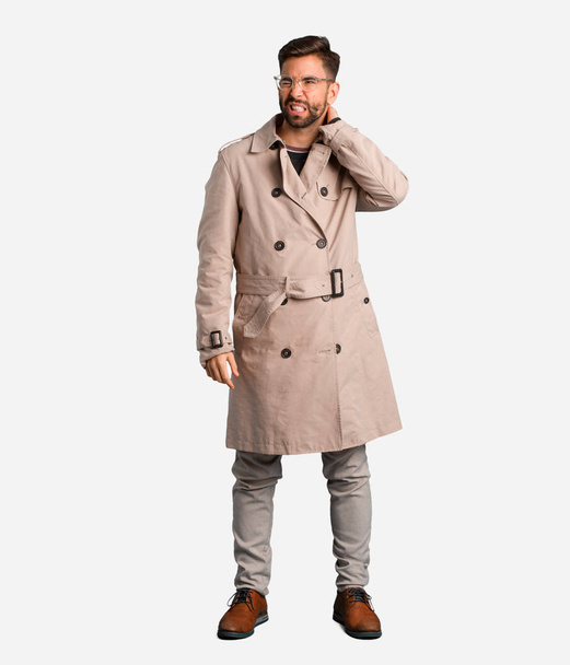 Young man wearing trench coat suffering neck pain - Foto, afbeelding