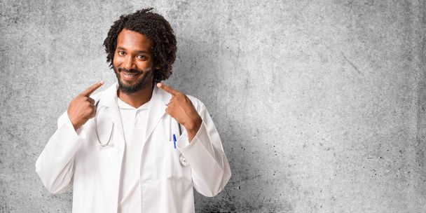 Handsome african american medical doctor smiles, pointing mouth, concept of perfect teeth, white teeth, has a cheerful and jovial attitude - Photo, Image