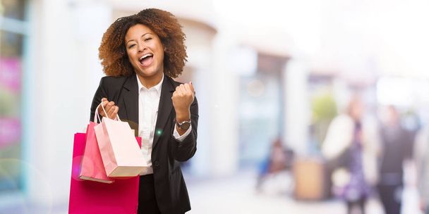 Fiatal fekete gazdaság bevásárló táskák, meglepett, és döbbenten nő - Fotó, kép