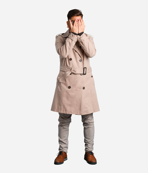 Jovem vestindo casaco de trincheira se sente preocupado e assustado
 - Foto, Imagem