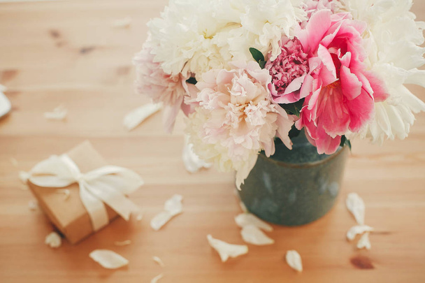 Stijlvolle roze en witte pioenrozen in vaas en gift box met lint  - Foto, afbeelding
