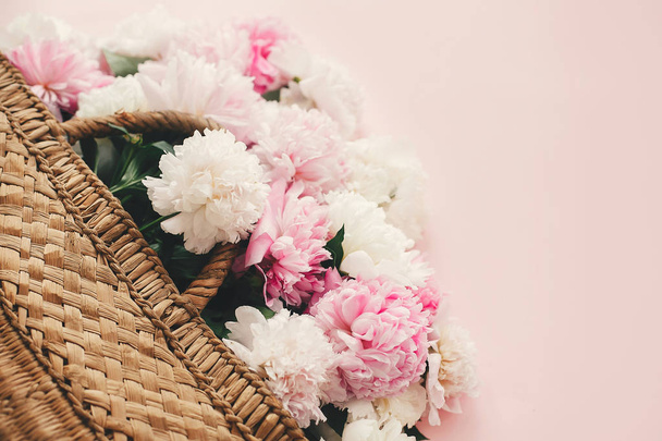 stilvoller Strohkorb mit rosa und weißen Pfingstrosen auf rosa - Foto, Bild