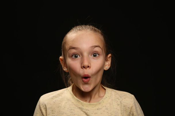 Genç Kız 9-12 yaş arası, çerçeve, duygusal sürpriz, stüdyo portre siyah bir arka plan üzerinde seyir - Fotoğraf, Görsel