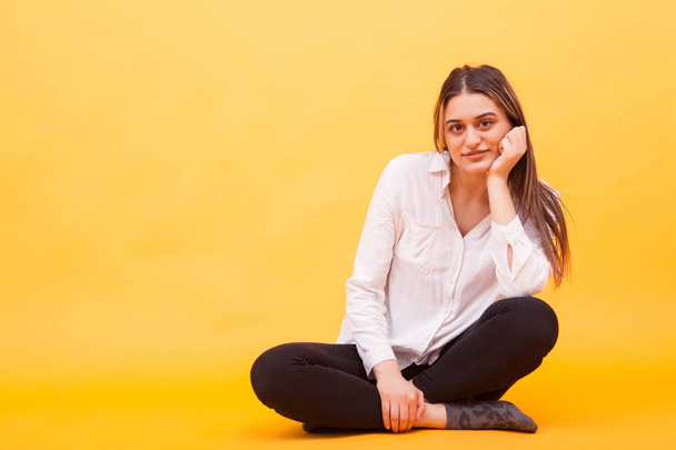 Beautiful young girl in white shirt smilling in studio over yellow background - Photo, Image