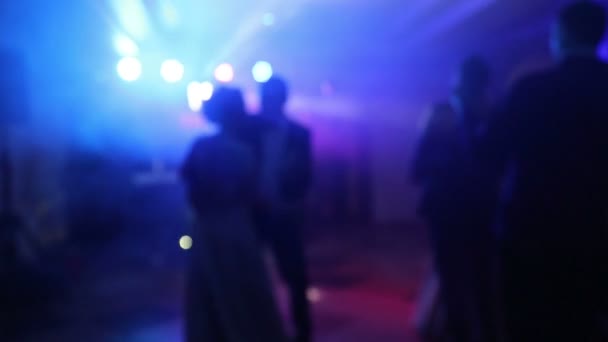 Silhouette of young people who kiss. Light devices shine with colored rays that highlight the silhouette of young people. Silhouette kiss during dance - Footage, Video