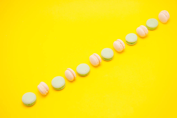 Assorted row of french macaroons over yellow background - Foto, Imagem