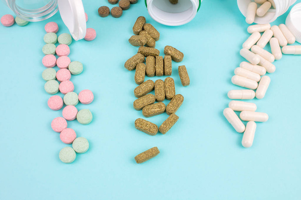 opened bottles with different pills on blue background - Foto, afbeelding