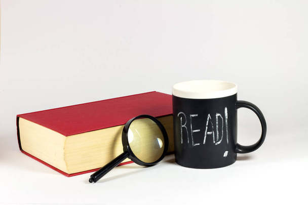 red book, magnifying glass and cup with read me lettering on white background - Valokuva, kuva