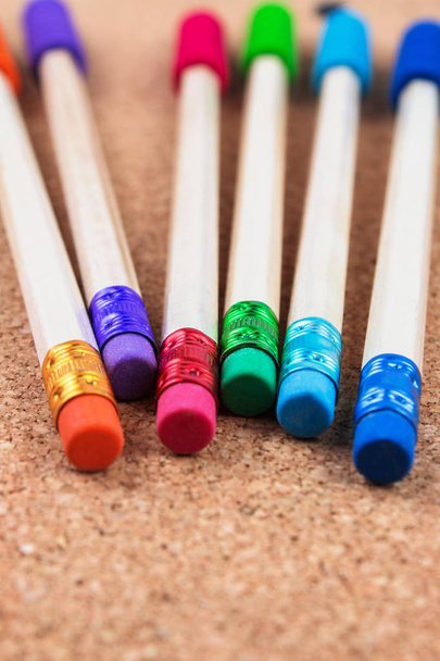 lápices de madera con borradores de colores sobre fondo de corcho
 - Foto, imagen