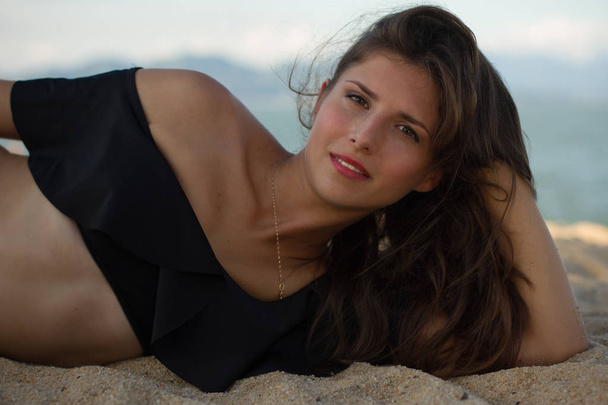 Beautiful brunette woman lying and relaxing on the beach - Valokuva, kuva
