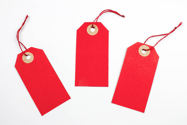 Kırmızı kağıt Etiketler üzerinde beyaz izole dizeleri ile bağlı - Fotoğraf, Görsel