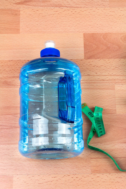 спортивна пляшка та вимірювальна стрічка на дерев'яному фоні
 - Фото, зображення