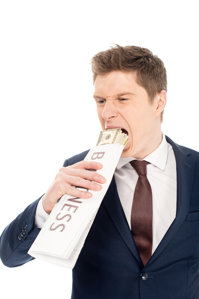 young businessman biting dollar banknotes wrapped in business newspaper, isolated on white - Photo, Image