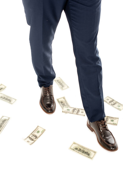 abgeschnittene Ansicht eines Geschäftsmannes mit Dollarnoten unter den Füßen, isoliert auf weiß - Foto, Bild