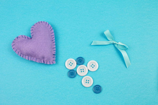 верхний вид войлока сердца с луком и кнопки на синем фоне
  - Фото, изображение