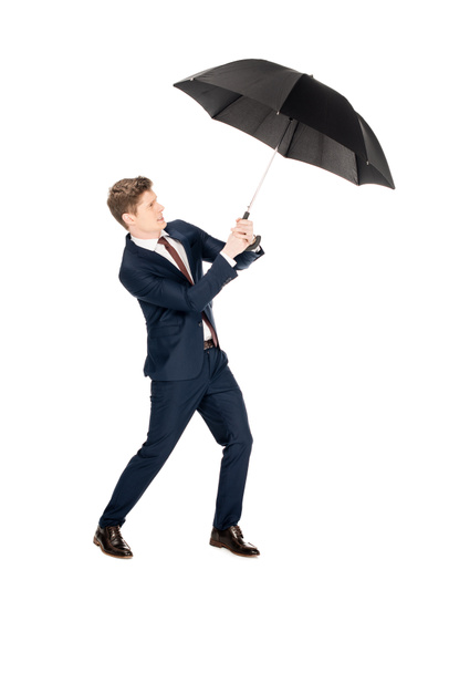 stylish businessman holding umbrella at windy weather isolated on white - Фото, зображення