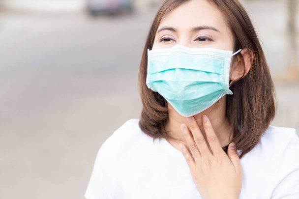 Woman wearing mask with sore throat, health care and medical concept - Photo, Image