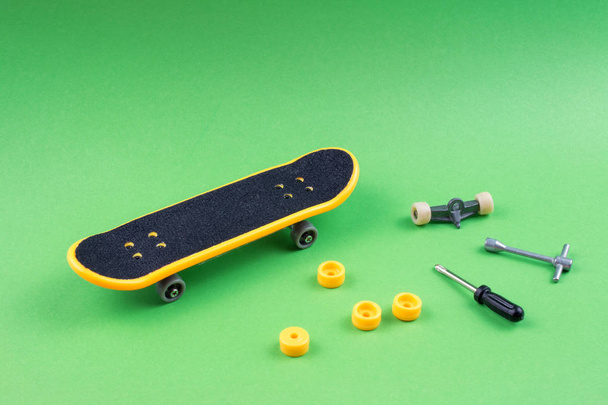Mini-Skateboard-Spielzeug mit Werkzeugen auf grünem Hintergrund - Foto, Bild