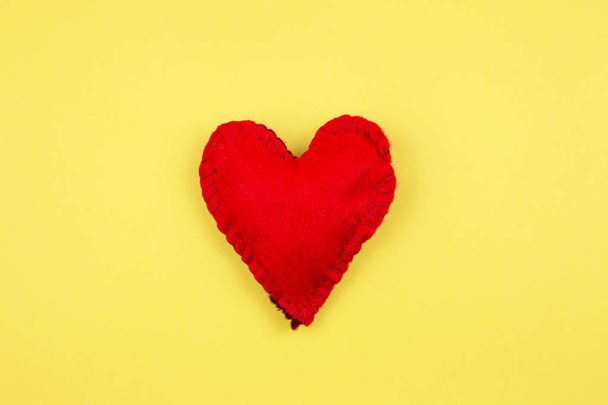 vista dall'alto del cuore di feltro rosso su sfondo giallo
  - Foto, immagini