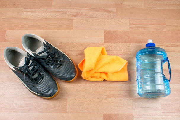 sportschoenen, fles en handdoek op houten achtergrond - Foto, afbeelding