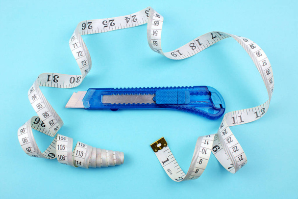 Blue Plastic Cutter and measuring tape on Paper background - Photo, Image