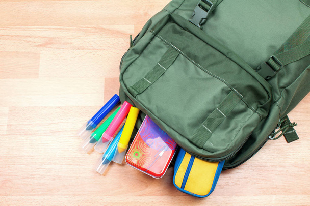 primer plano de la mochila con marcadores de colores y suministros de arte en la superficie de madera
 - Foto, imagen