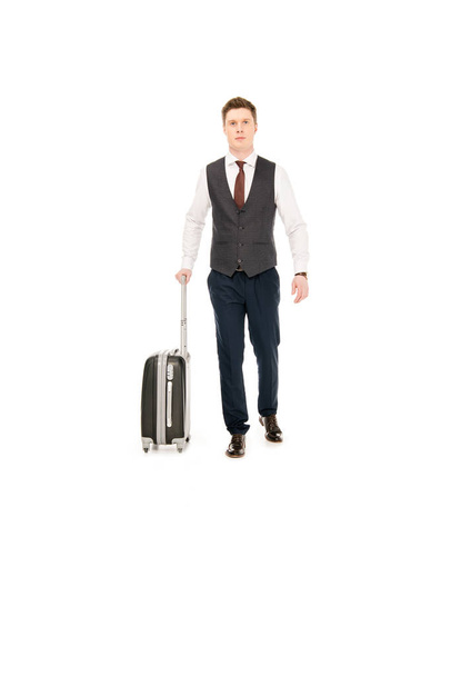白で隔離、ビジネス旅行のためのスーツケースを持って歩くハンサムなスタイリッシュなビジネスマン  - 写真・画像