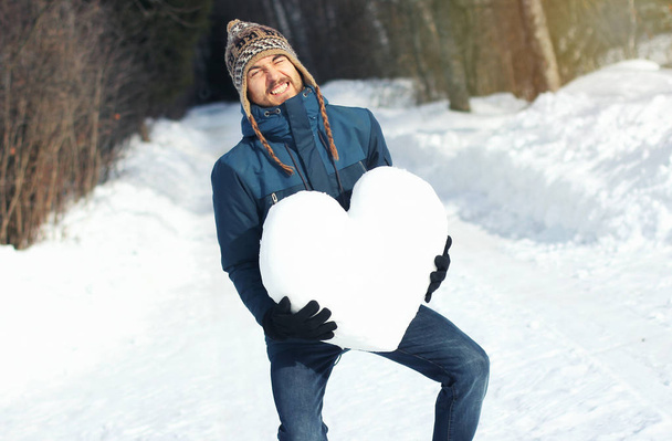 Comical man with great difficulty holding huge heavy heart made  - Photo, image