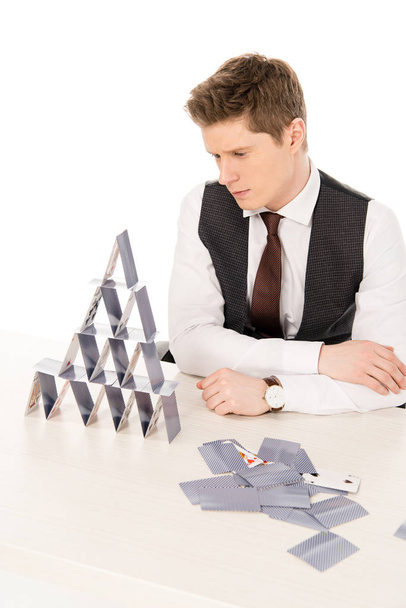 przystojny koncentratu manager, udostępniając piramidę z kart do gry na białym tle - Zdjęcie, obraz