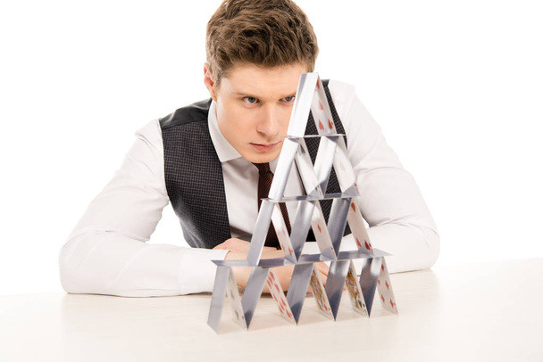 focused man making pyramid from playing cards isolated on white - Photo, Image