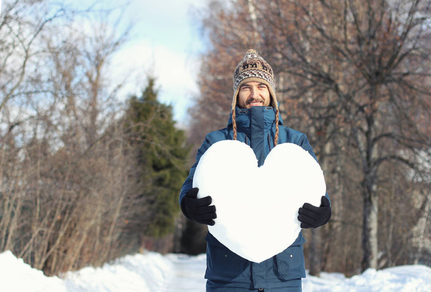 Handsome smiling bearded hipster man holding a big heart made of - Foto, imagen
