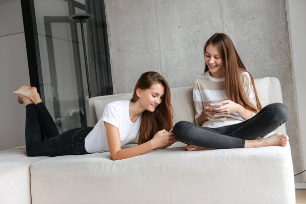 Dos muchachas adolescentes jóvenes encantadoras usando teléfonos móviles
 - Foto, imagen